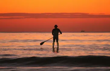 Photo by <a href="https://unsplash.com/@lilianschiffer?utm_content=creditCopyText&utm_medium=referral&utm_source=unsplash">Lilian Jeane Schiffer</a> on <a href="https://unsplash.com/photos/a-man-standing-on-a-surfboard-in-the-ocean-at-sunset--TpopT-2ZdM?utm_content=creditCopyText&utm_medium=referral&utm_source=unsplash">Unsplash</a>;